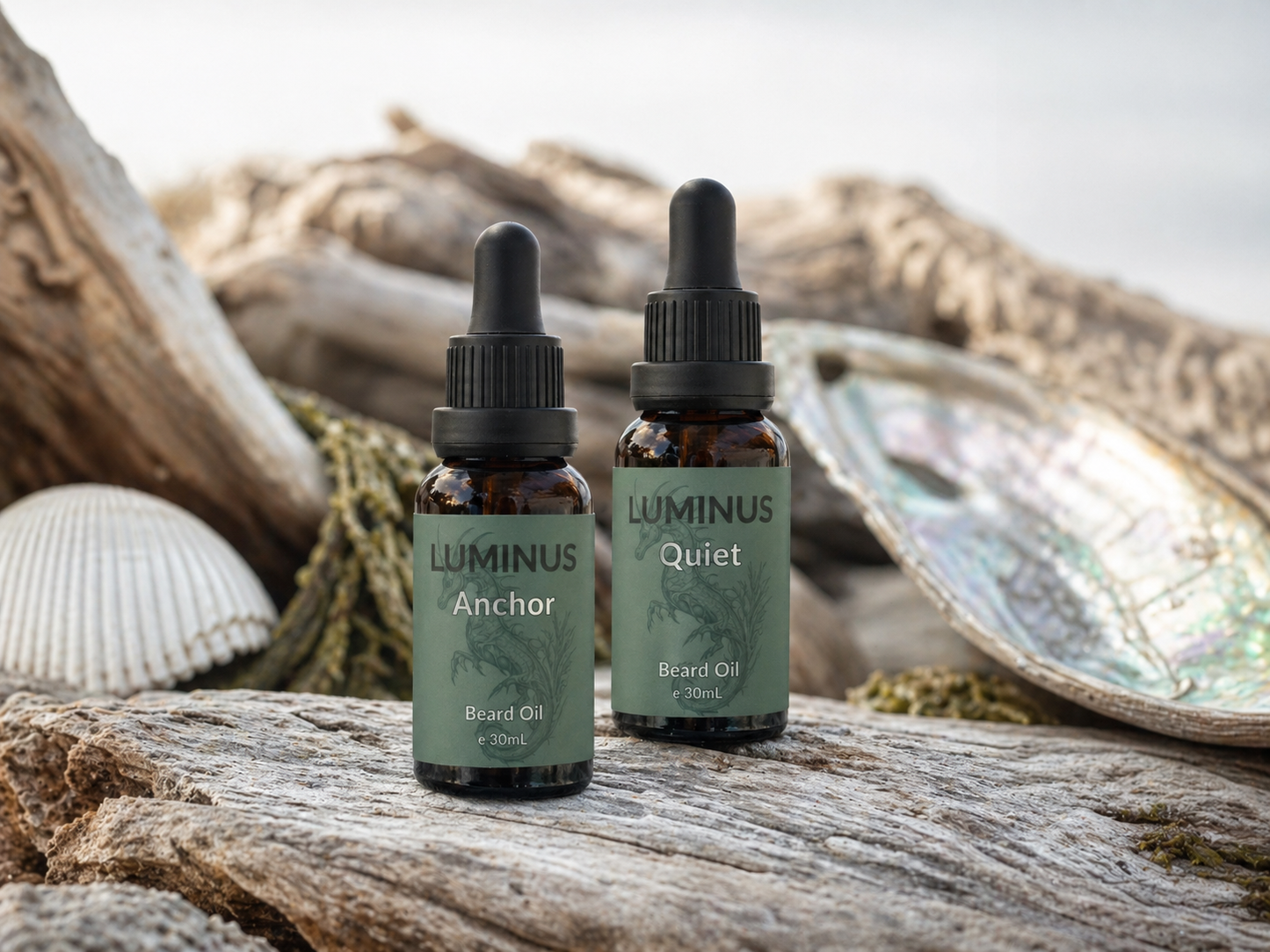 A bottle each of Anchor and Quiet beard oils displayed on driftwood and shells