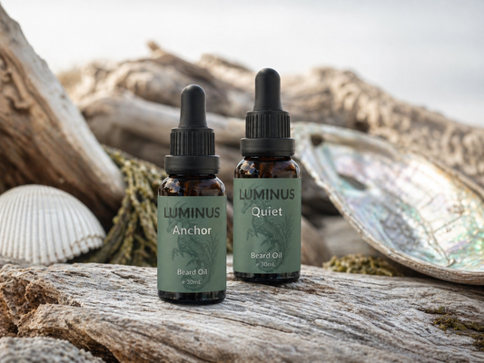 A bottle each of Anchor and Quiet beard oils displayed on driftwood and shells